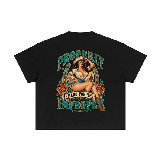 A black short-sleeve t-shirt shown from the back, featuring a large vintage-style pin-up graphic with the text 'PROPERLY MADE FOR THE IMPROPE' in teal and tan tones.