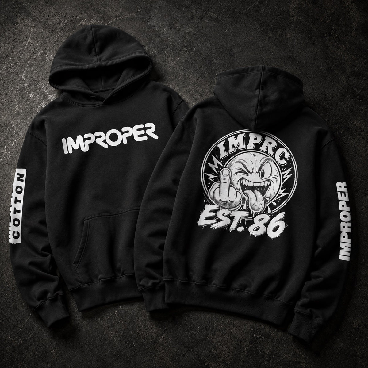 Two black hoodies shown flat on a dark textured background, displaying the front and back designs. The front features the word 'IMPROPER' in white across the chest, and the back features a large circular graphic of a cartoon face giving a middle finger with 'IMPROPER EST.