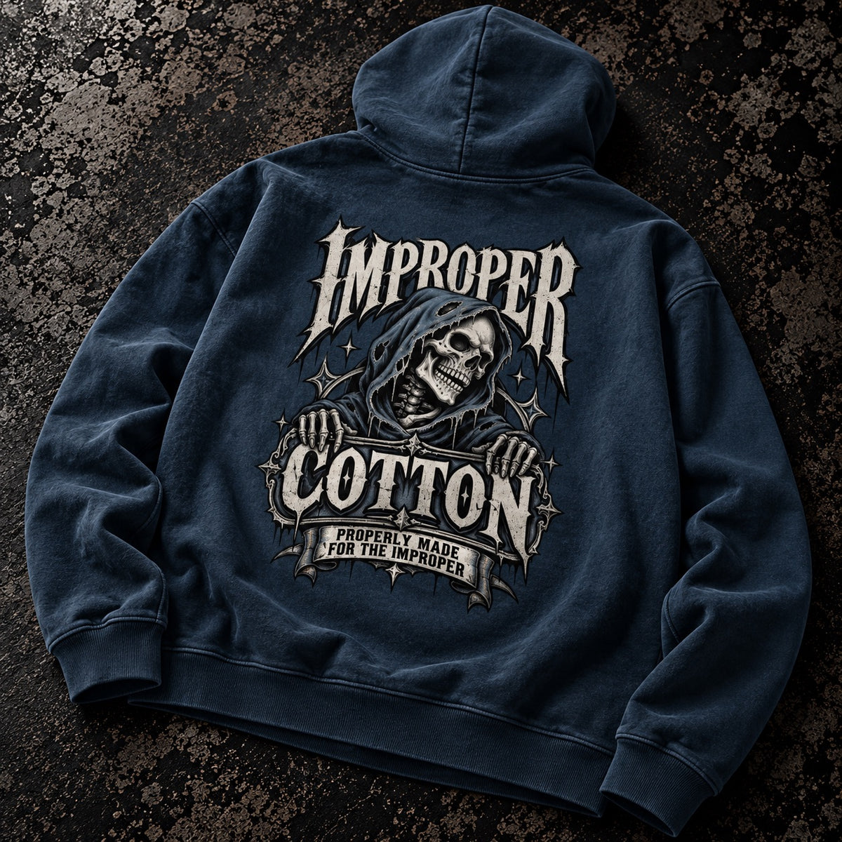 A dark navy blue hooded sweatshirt laid flat on a textured dark background, featuring a large back graphic with a hooded skeleton and the words 'Improper Cotton' in distressed white and gray lettering.