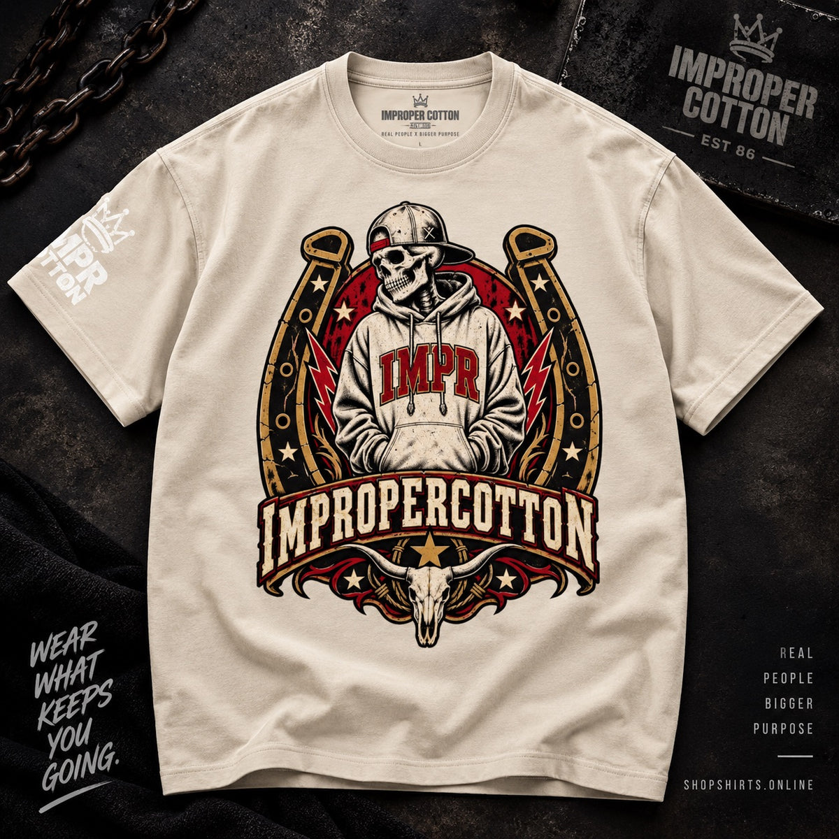 A cream-colored t-shirt featuring a large graphic print of a skull in a cowboy hat inside a horseshoe with the text 'IMPR' and 'IMPROPERCOTTON'. The shirt is laid flat on a dark textured background with decorative chain and text overlays.
