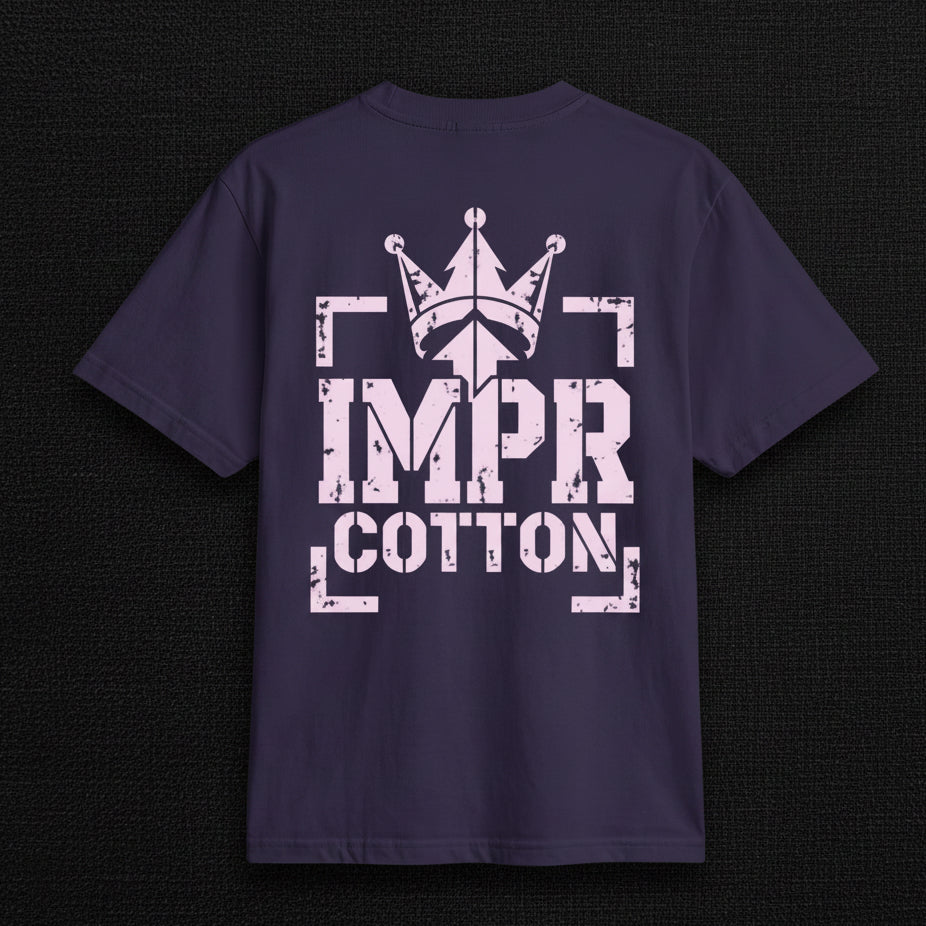 A dark navy blue short-sleeve t-shirt with a distressed light pink graphic on the front. The graphic features a crown above the text 'IMPR COTTON' enclosed in bracket-like shapes.