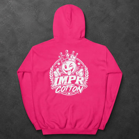 A bright pink hoodie shown from the back, featuring a large white graphic print with a cartoon face, crown, laurel wreath, and the words “IMPR COTTON.” The hoodie is laid flat on a dark textured background.