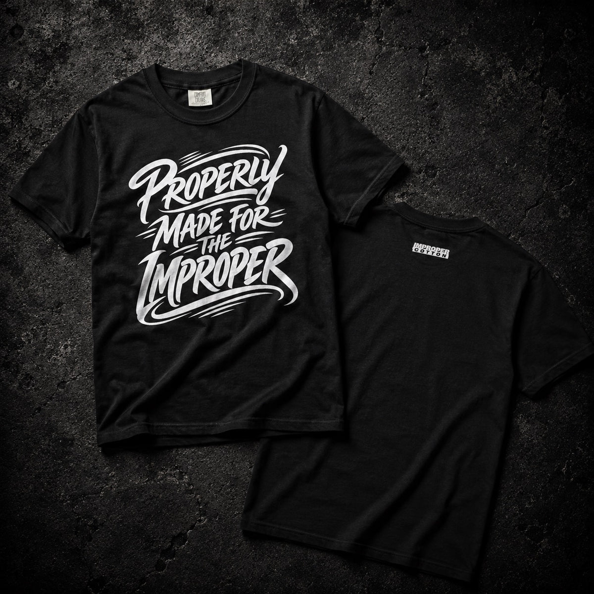 Two black short-sleeve t-shirts laid flat on a dark textured background. The front shirt shows a large white graphic reading 'Property Made for the Improper,' and the back shirt shows a small white 'PROPERTY' logo near the upper back.