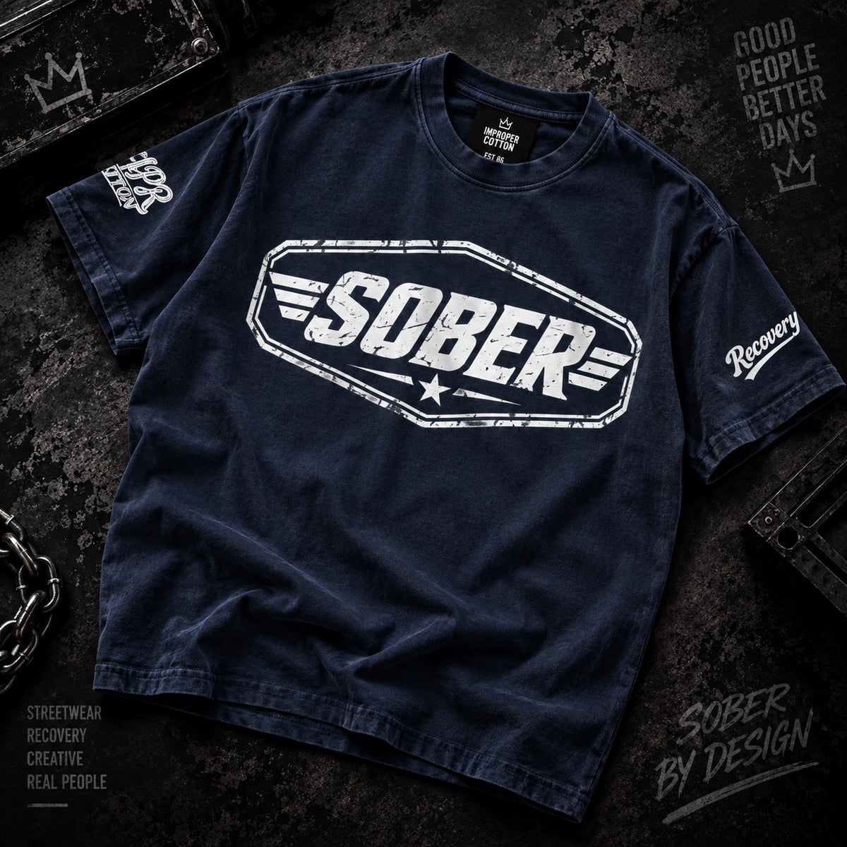 A dark navy blue t-shirt with a distressed white graphic reading 'SOBER' on the chest, laid flat on a dark textured background with streetwear-style props and text.