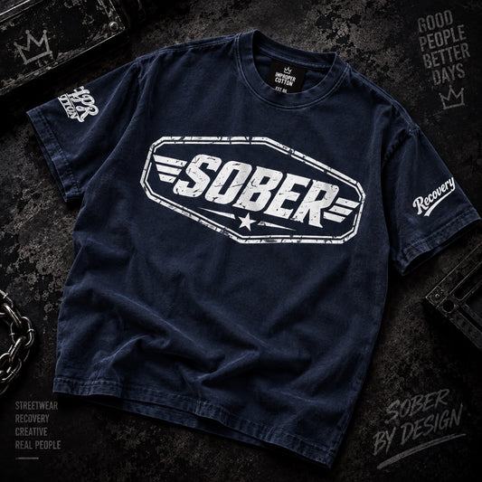 A dark navy blue t-shirt with a distressed white graphic reading 'SOBER' on the chest, laid flat on a dark textured background with streetwear-style props and text.
