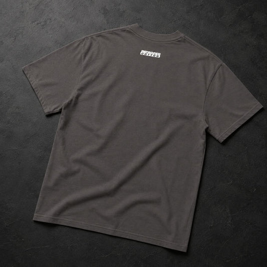 A dark gray crewneck t-shirt laid flat on a dark textured background, featuring a small white rectangular graphic printed on the upper back.