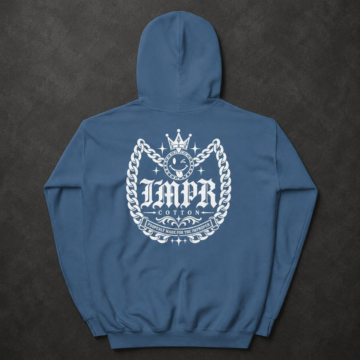 A blue pullover hoodie shown from the back, featuring a large white graphic print with a crown, chain, and the text 'IMPR COTTON' on a dark textured background.