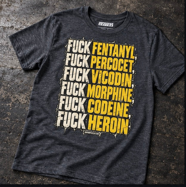 A dark heather gray graphic t-shirt laid flat on a dark textured surface. The shirt features a large vertical text graphic in white and yellow spray-paint style reading 'FUCK FENTANYL.