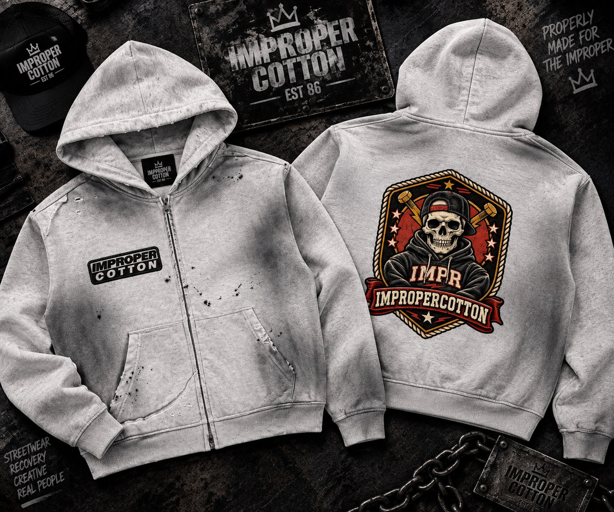 Two light gray zip-up hoodies shown from front and back on a dark textured background. The front hoodie has a small rectangular 'Improper Cotton' patch on the left chest and a distressed splatter effect.