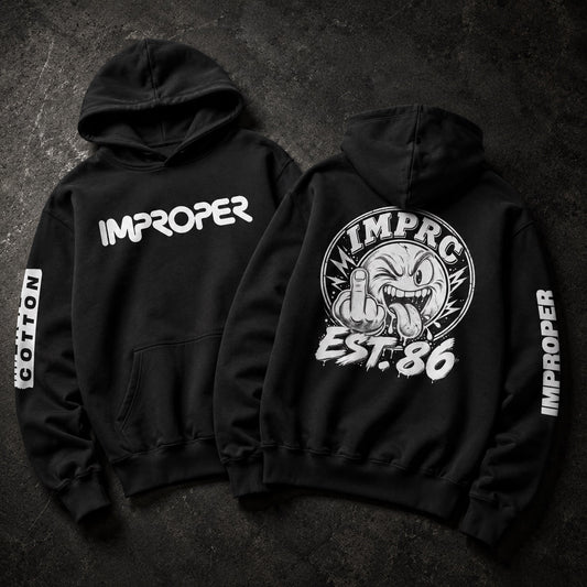 Two black hoodies shown flat on a dark textured background, displaying the front and back designs. The front features the word 'IMPROPER' in white across the chest, and the back features a large circular graphic of a cartoon face giving a middle finger with 'IMPROPER EST.