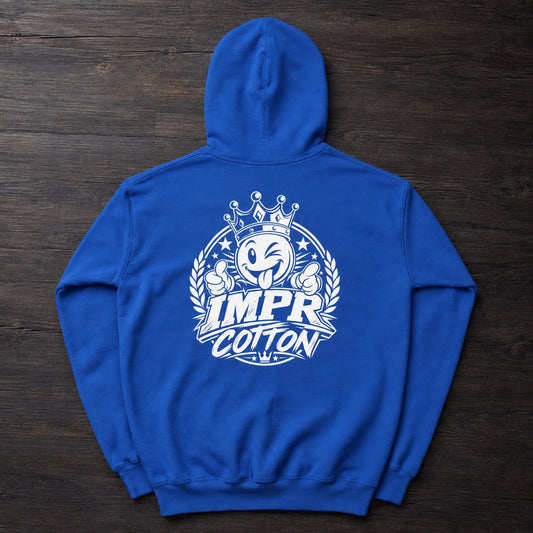 A royal blue hoodie laid flat on a dark wood background, featuring a large white graphic on the back with a cartoon face wearing a crown and the words “IMPR COTTON.”.