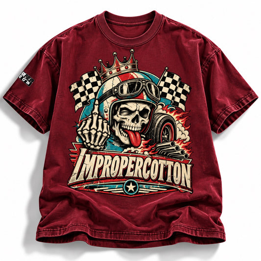A maroon short-sleeve graphic t-shirt featuring a skull in a racing helmet with checkered flags, flames, and the text 'IMPROPERCOTTON' on the front.