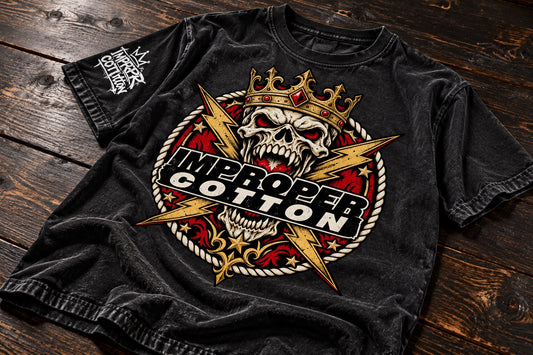 Black vintage wash Improper Cotton crowned skull graphic T-shirt laid slightly angled on a clean tabletop with a soft cast shadow, showcasing the bold red, gold and cream streetwear design.
