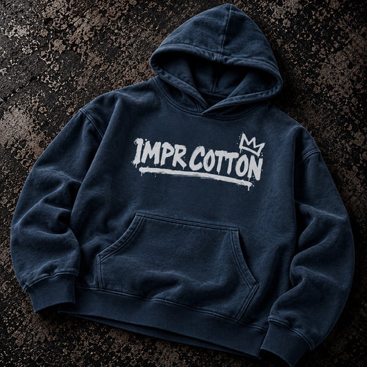 A dark navy blue hooded sweatshirt with a white 'IMPR. COTTON' graphic and crown logo on the chest, laid flat on a textured dark background.
