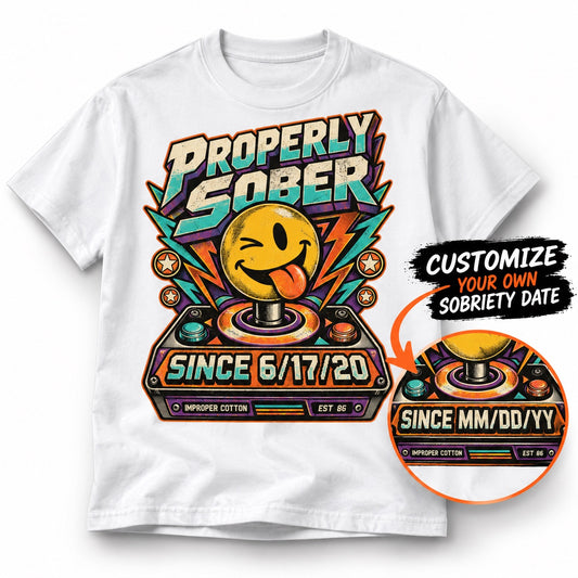White Improper Cotton Properly Sober T-shirt featuring a colorful retro smiley graphic and personalized sobriety date, shown on a clean white background with a custom date preview and soft shadow.