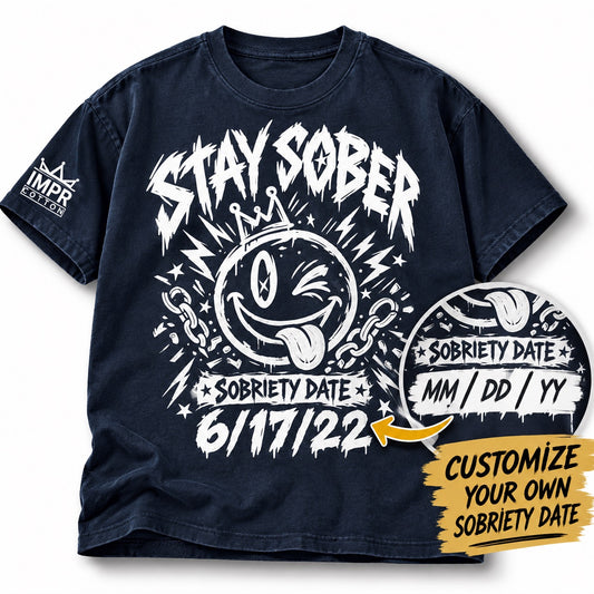 Dark navy Improper Cotton Stay Sober T-shirt featuring a crowned winking smiley graphic and personalized sobriety date, shown on a clean white background with soft shadows and a custom date preview.