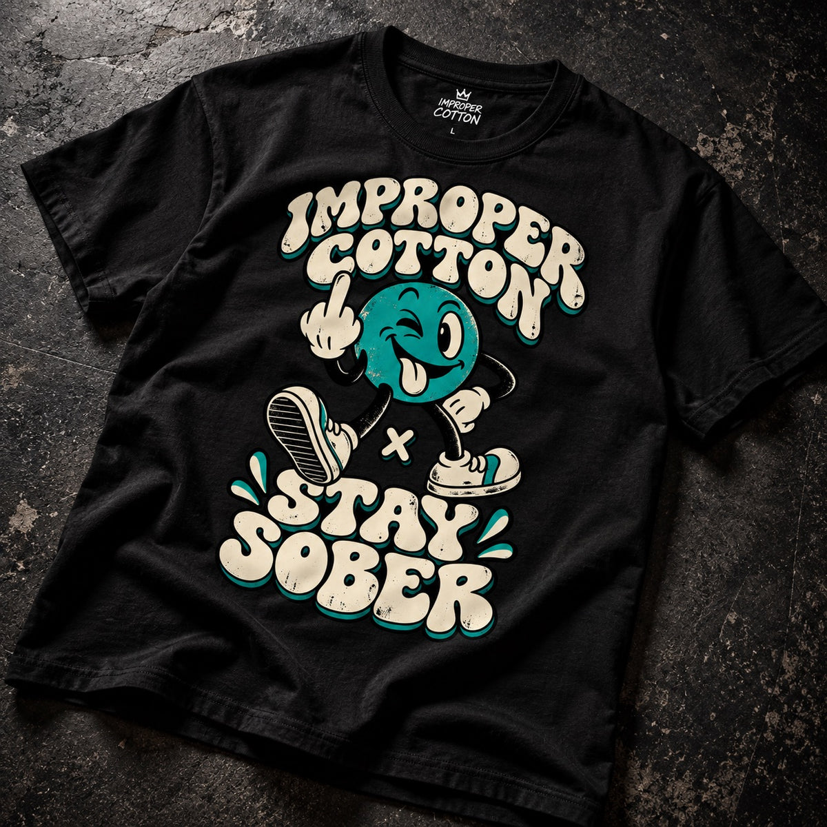 A black graphic t-shirt laid flat on a dark textured surface. The shirt features a cartoon character with a teal face and white sneakers, surrounded by the text 'IMPROPER COTTON' and 'STAY SOBER' in a cream-colored retro font with teal outlines.