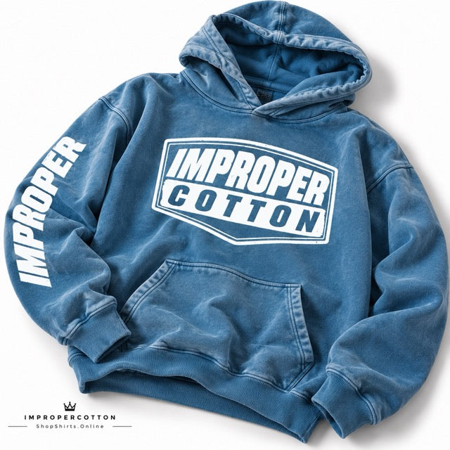 A blue acid-wash pullover hoodie with a white 'IMPROPER COTTON' logo on the chest and 'IMPROPER' printed down one sleeve, shown on a white background.