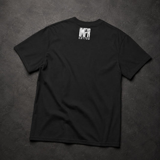 A black short-sleeve t-shirt laid flat on a dark textured background, featuring a white vertical graphic print on the upper back that reads 'IMPR' above 'COTTON'.