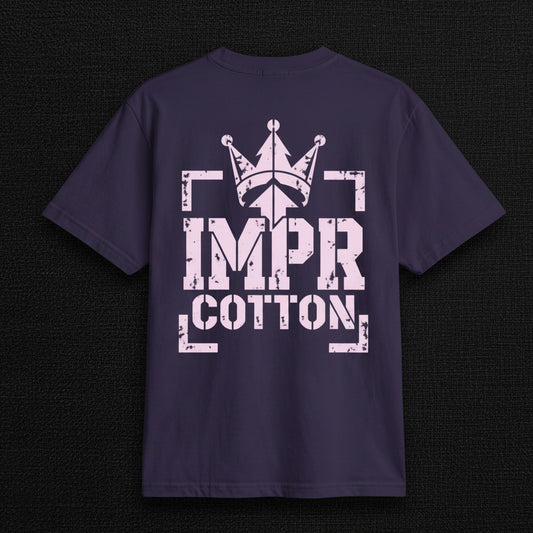 A dark navy blue short-sleeve t-shirt with a distressed light pink graphic on the front. The graphic features a crown above the text 'IMPR COTTON' enclosed in bracket-like shapes.
