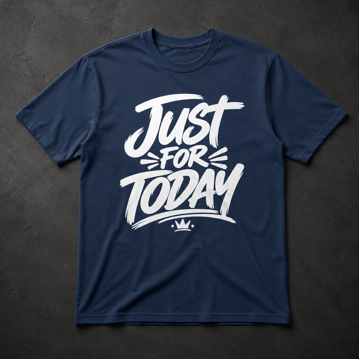 A navy blue short-sleeve t-shirt with a white graphic print reading 'Just FOR TODAY' and a small crown underneath, laid flat on a dark textured background.