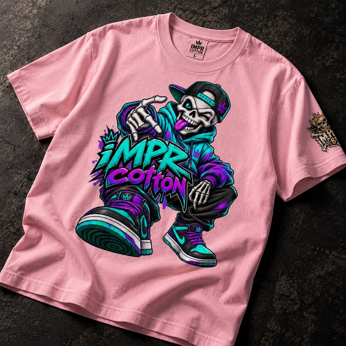 A pink short-sleeve t-shirt laid flat on a dark textured surface, featuring a large colorful graphic of a cartoon skeleton wearing a cap and sneakers with the text 'IMPR COTTON' in bold purple and teal lettering.