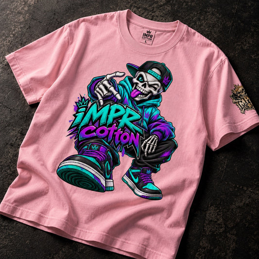 A pink short-sleeve t-shirt laid flat on a dark textured surface, featuring a large colorful graphic of a cartoon skeleton wearing a cap and sneakers with the text 'IMPR COTTON' in bold purple and teal lettering.