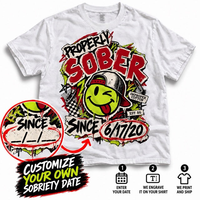 White short-sleeve graphic T-shirt shown on a light gray background with a large distressed front print. The design features red 'SOBER' lettering, a yellow smiley face wearing a cap, black and green graffiti-style text, and a customizable date circle reading '6/17/20'.