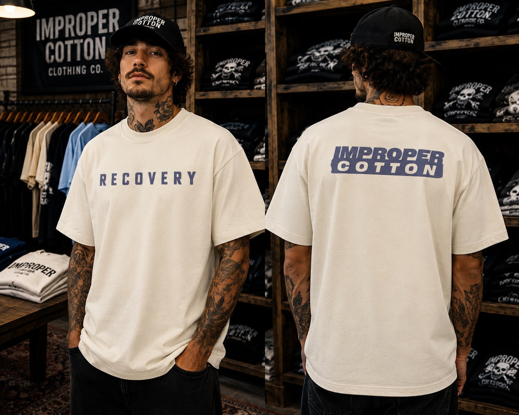 Two models wearing an off-white t-shirt with 'RECOVERY' printed on the front and 'IMPROPER COTTON' on the back, standing in a retail store.