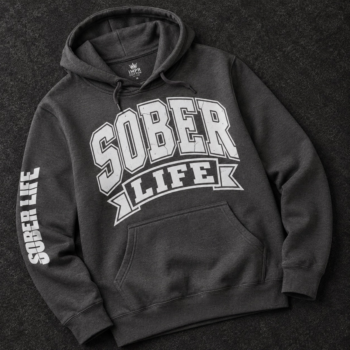 A dark charcoal gray hoodie laid flat on a dark textured background, featuring a large white 'SOBER LIFE' graphic across the chest and 'SOBER LIFE' printed down one sleeve.
