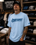 A model wearing a baby blue signature impropercotton improper brand T-shirt
