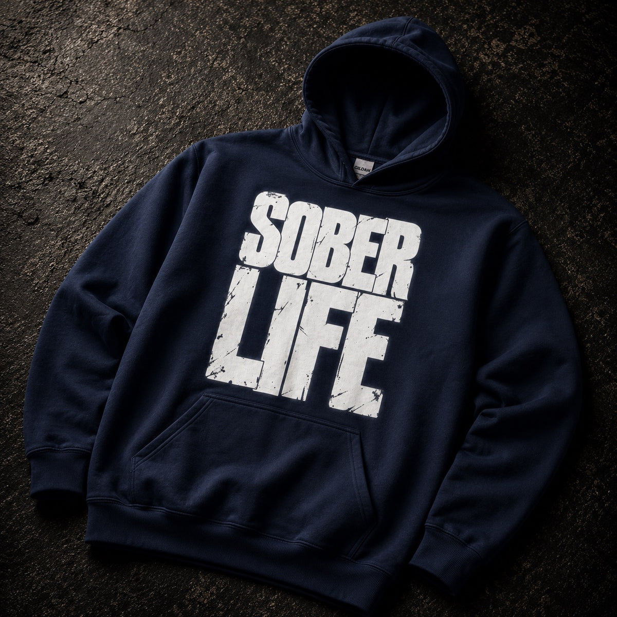A navy blue pullover hoodie with a large distressed white 'SOBER LIFE' graphic printed on the front, laid flat on a dark textured background.