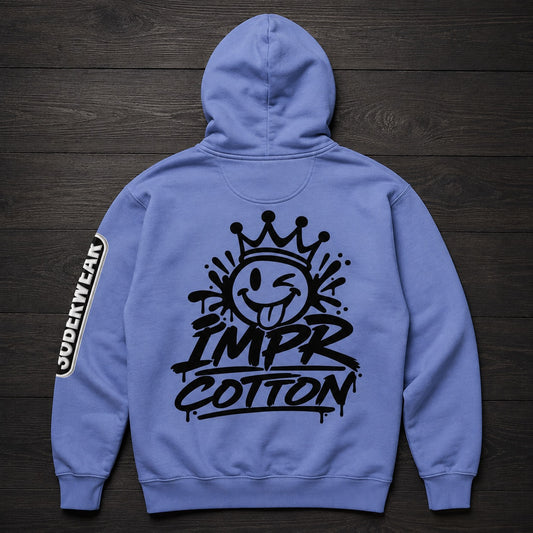 A light blue hoodie shown from the back, laid flat on a dark wood background. The back features a large black graphic of a winking smiley face under a crown with the text 'IMPR COTTON'.