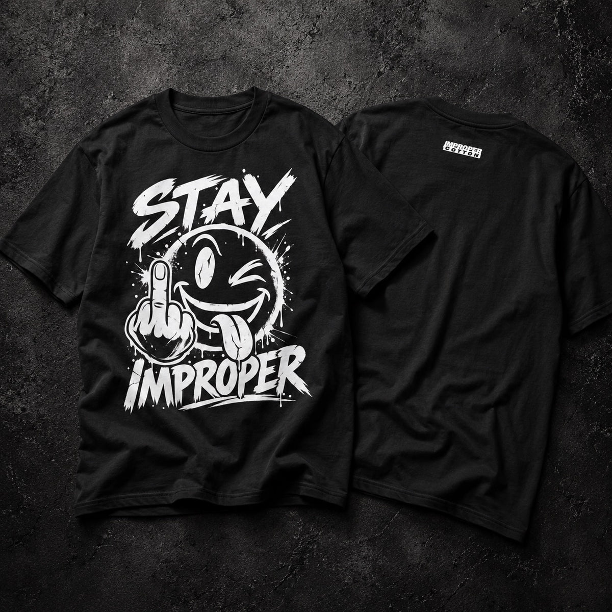 Two black short-sleeve graphic T-shirts laid flat on a dark textured background, showing the front and back views. The front features a large white graphic with the words 'STAY IMPROPER' and a cartoon face making a middle finger gesture.