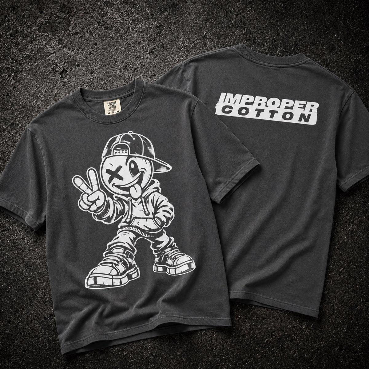 A dark charcoal gray t-shirt shown from both front and back. The front features a large white graphic of a cartoon character wearing a cap and giving a peace sign.