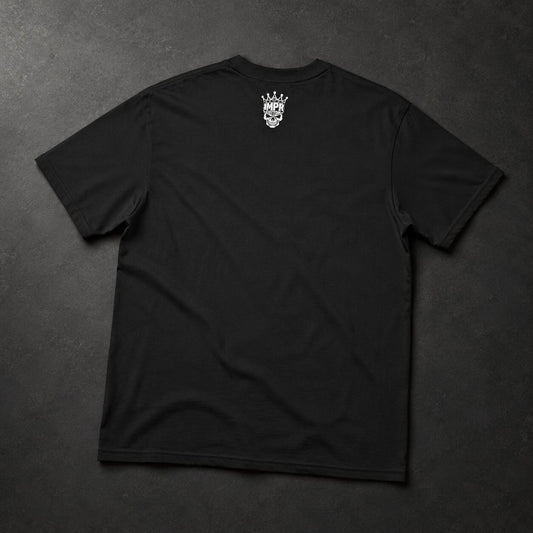 A black short-sleeve t-shirt laid flat on a dark textured background, featuring a small white graphic of a skull wearing a crown printed on the upper back.