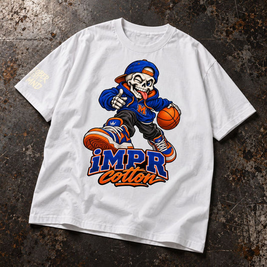 A white short-sleeve t-shirt laid flat on a dark, textured industrial surface. The shirt features a large graphic of a cartoon skeleton wearing a blue New York Mets cap and sneakers, holding a basketball, with the text 'iMPR Cotton' printed below in blue and orange.