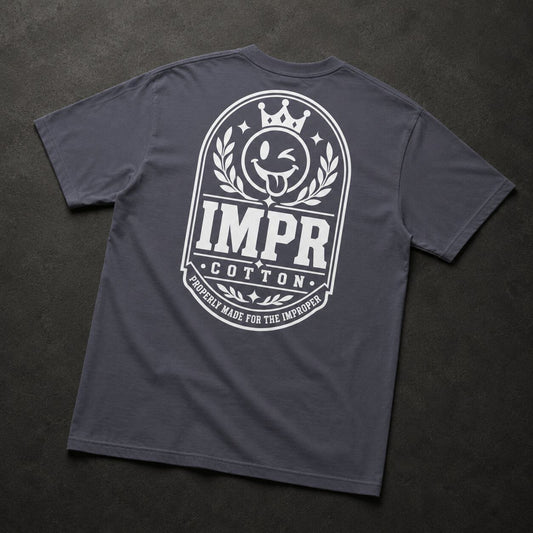 A dark gray crewneck t-shirt shown from the back, featuring a large white graphic print with a crown, laurel wreath, and the text 'IMPR COTTON' and 'PROPERLY MADE FOR THE IMPROPER'.