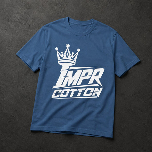 A blue short-sleeve t-shirt with a white graphic print featuring a crown and the text 'IMPR COTTON', laid flat on a dark textured background.