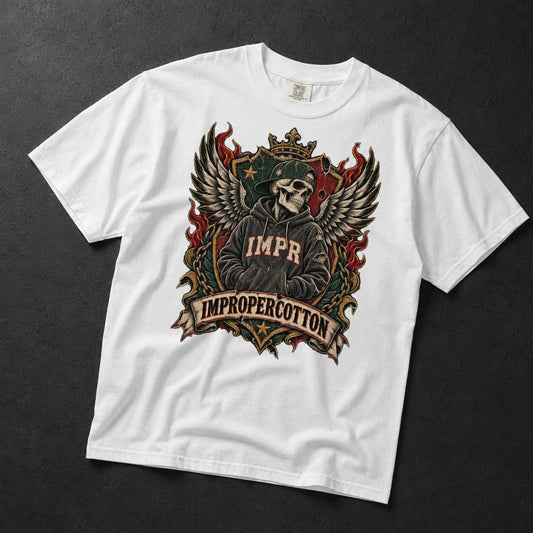 A white short-sleeve graphic t-shirt laid flat on a dark textured background. The shirt features a large front graphic of a crowned skull wearing a robe with 'IMPR' on the chest, flanked by wings, with a banner reading 'IMPROPERCOTTON'.