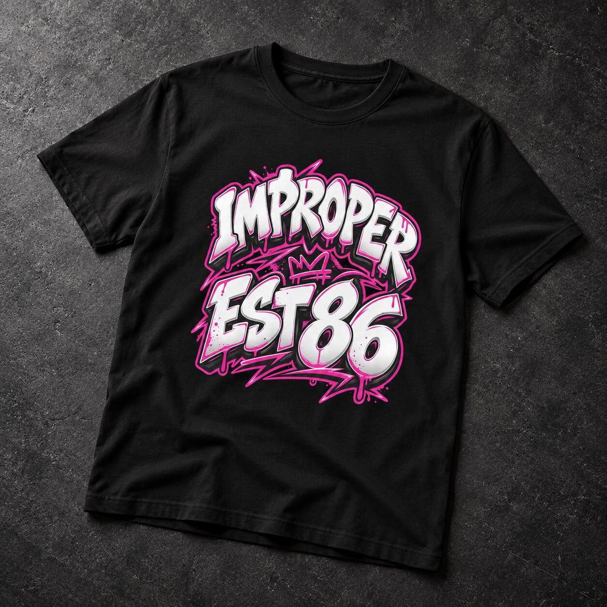 A black short-sleeve t-shirt laid flat on a dark textured background, featuring a large graffiti-style graphic on the front that reads 'IMPROPER EST 86' in white with bright pink outlines.
