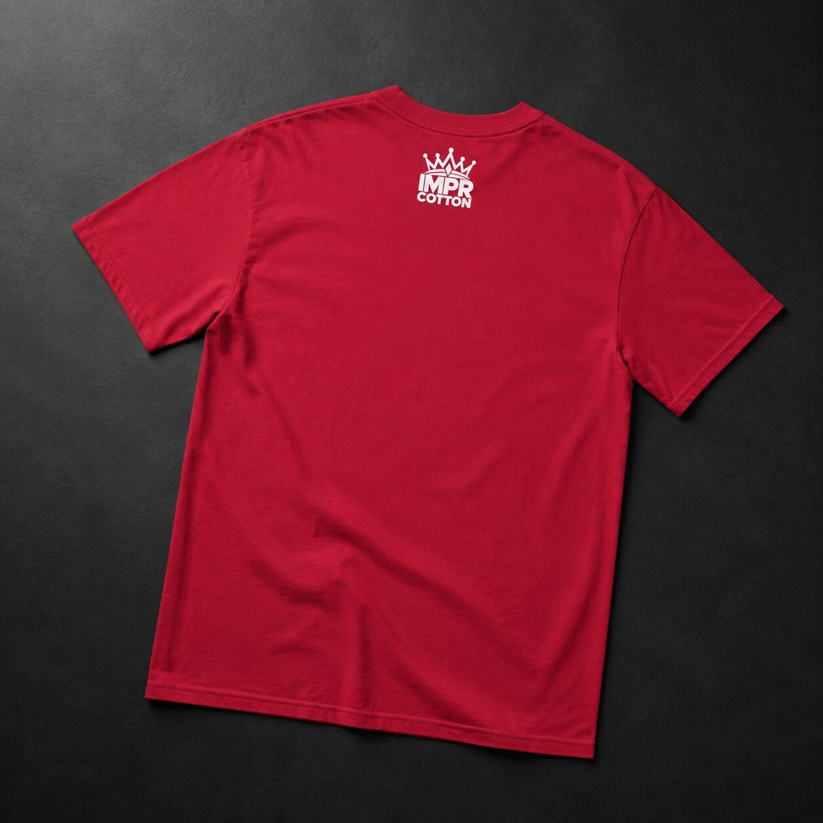 A red short-sleeve t-shirt laid flat on a dark textured background, showing a white crown and 'MPR COTTON' logo printed on the upper back.