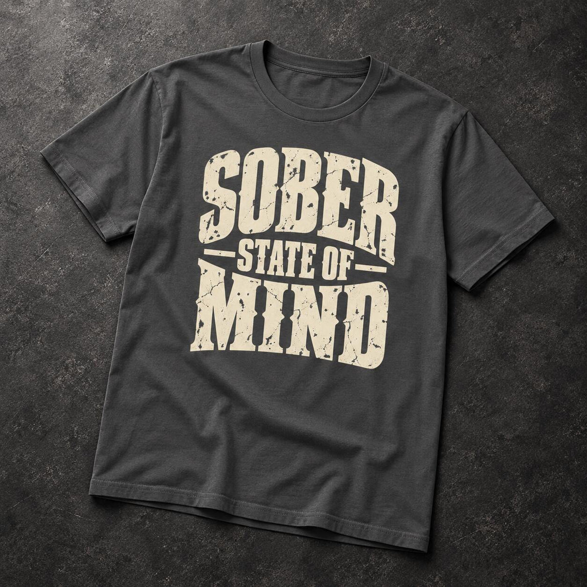 A dark charcoal gray t-shirt with a distressed cream-colored graphic reading 'SOBER STATE OF MIND' laid flat on a dark textured background.