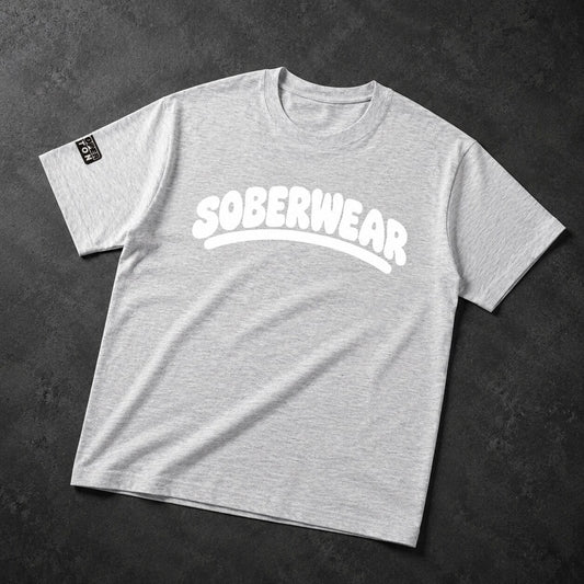 A light heather gray crewneck t-shirt with 'SOBERWEAR' printed in white across the chest, laid flat on a dark textured background.