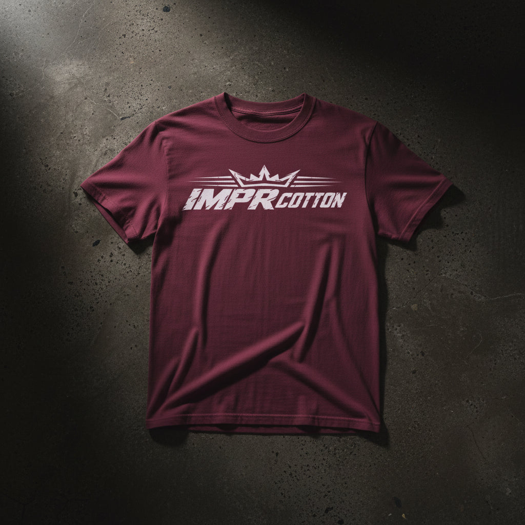 A short-sleeve crewneck t-shirt in maroon with a white graphic print on the chest reading 'IMPR COTTON' under a stylized crown, displayed on a clean white background.